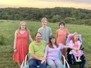 The Huff family of two parents, one boy, and three girls pose in a field.